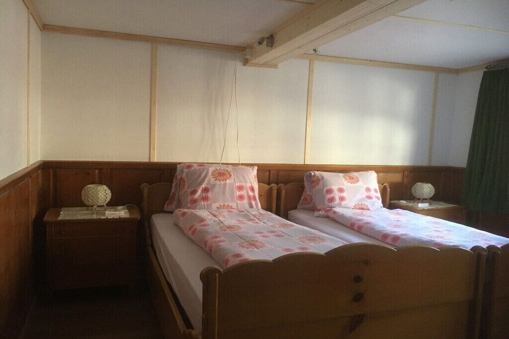 Ein Zimmer mit zwei hölzernen Betten, jeweils mit floralem Bettbezug und passenden Kissen. Zwei Nachttische mit Lampen sind ebenfalls vorhanden.