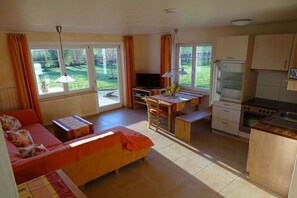 A compact living space with a sofa, dining table, and kitchenette. - Bioland farm Teufelsberg (Horgenzell)