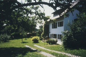 Una casa con un camino empedrado que lleva a la entrada, rodeada de follaje y árboles.
