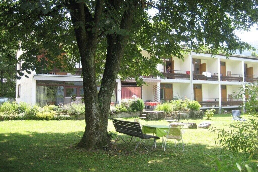 Ein Gebäude mit einer zweistöckigen Struktur, einem grünen Innenhof und einem Baum, der Schatten spendet.