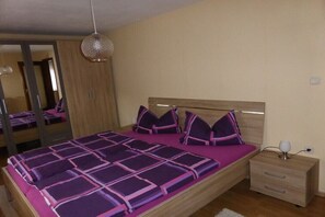 Een slaapkamer met een groot bed, een nachtkastje, een spiegel en een hanglamp.