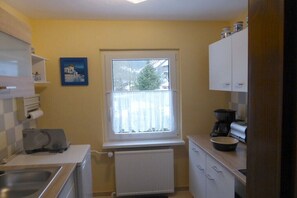 A compact kitchen with a window, a radiator, a sink, and cabinets. - Holiday home with 1 bedroom (Katzhütte)