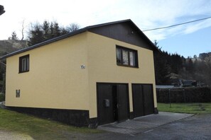 Een gebouw met twee verdiepingen, een plat dak, één zichtbaar raam en een deur.
