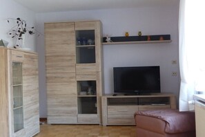 A living room with a TV, wooden cabinets, and a sofa. - Holiday home with 1 bedroom (Katzhütte)