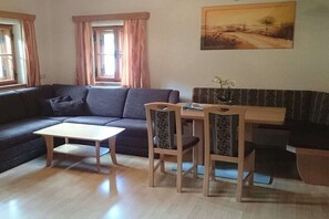 A living room with a sofa, a small table, and two chairs. There is a painting on the wall and a window with curtains. - Holiday apartment with 1 bedroom (Rauris)