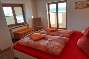 Un dormitorio con dos camas, una ventana, un radiador y una silla.