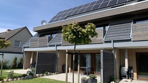 A modern two-story house with solar panels, a covered patio, and a well-maintained garden. - TRINCHEN in the home by the sea (Büsum)