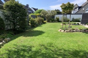 Ein gepflegter Garten mit Rasenfläche, Bäumen und einer Steingrenze.