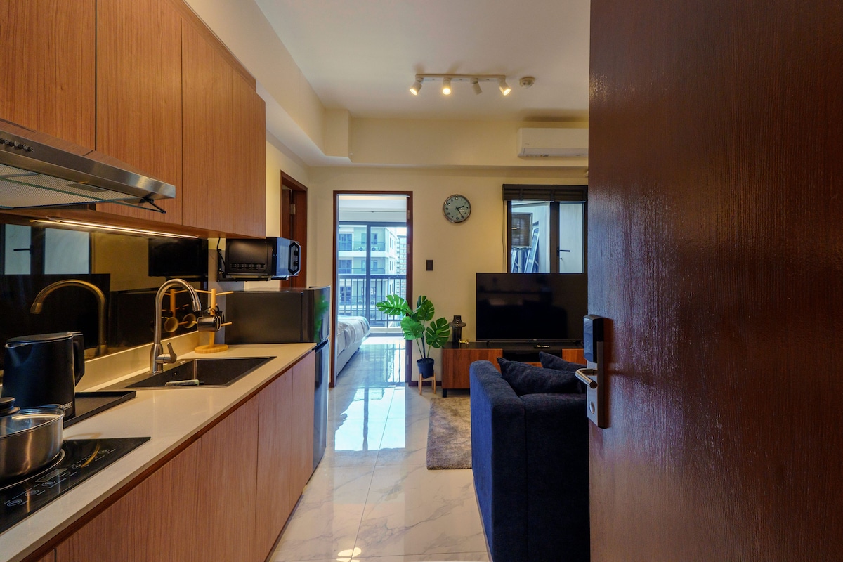 Una cocina moderna con electrodomésticos de acero inoxidable, un comedor con sofá y un amplio ventanal con vistas al exterior.