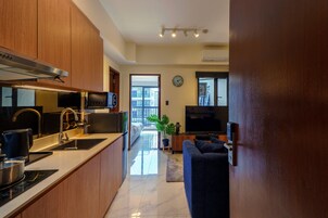 A modern kitchen with stainless steel appliances, a dining area with a sofa, and a large window providing a view of the outside.