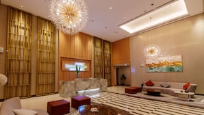 A modern hotel lobby with a reception desk, seating area, and decorative lighting. - SunnyPlace (Parañaque)