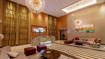 A modern hotel lobby with a reception desk, seating area, and decorative lighting.