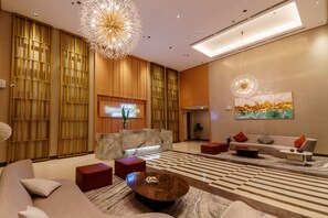 Un moderno vestíbulo de hotel con mostrador de recepción, área de descanso e iluminación decorativa.