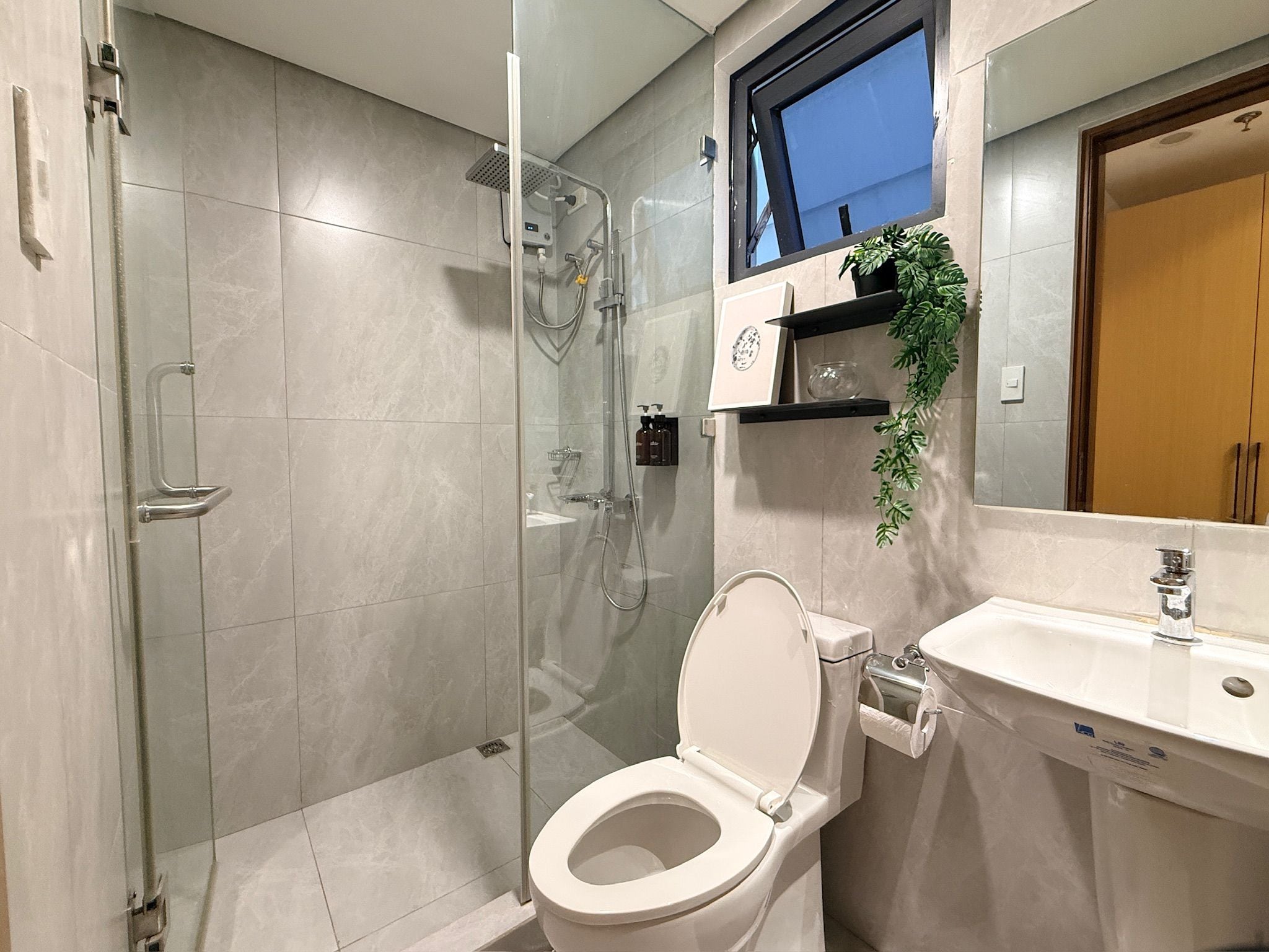 A modern bathroom with a glass-enclosed shower, a toilet, and a sink.