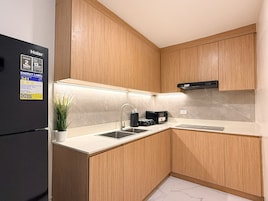 Una cocina moderna con armarios de madera, un refrigerador negro, un fregadero y una cafetera.
