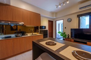 A modern kitchen with wooden cabinets, a built-in microwave, and a large island with a flat surface.