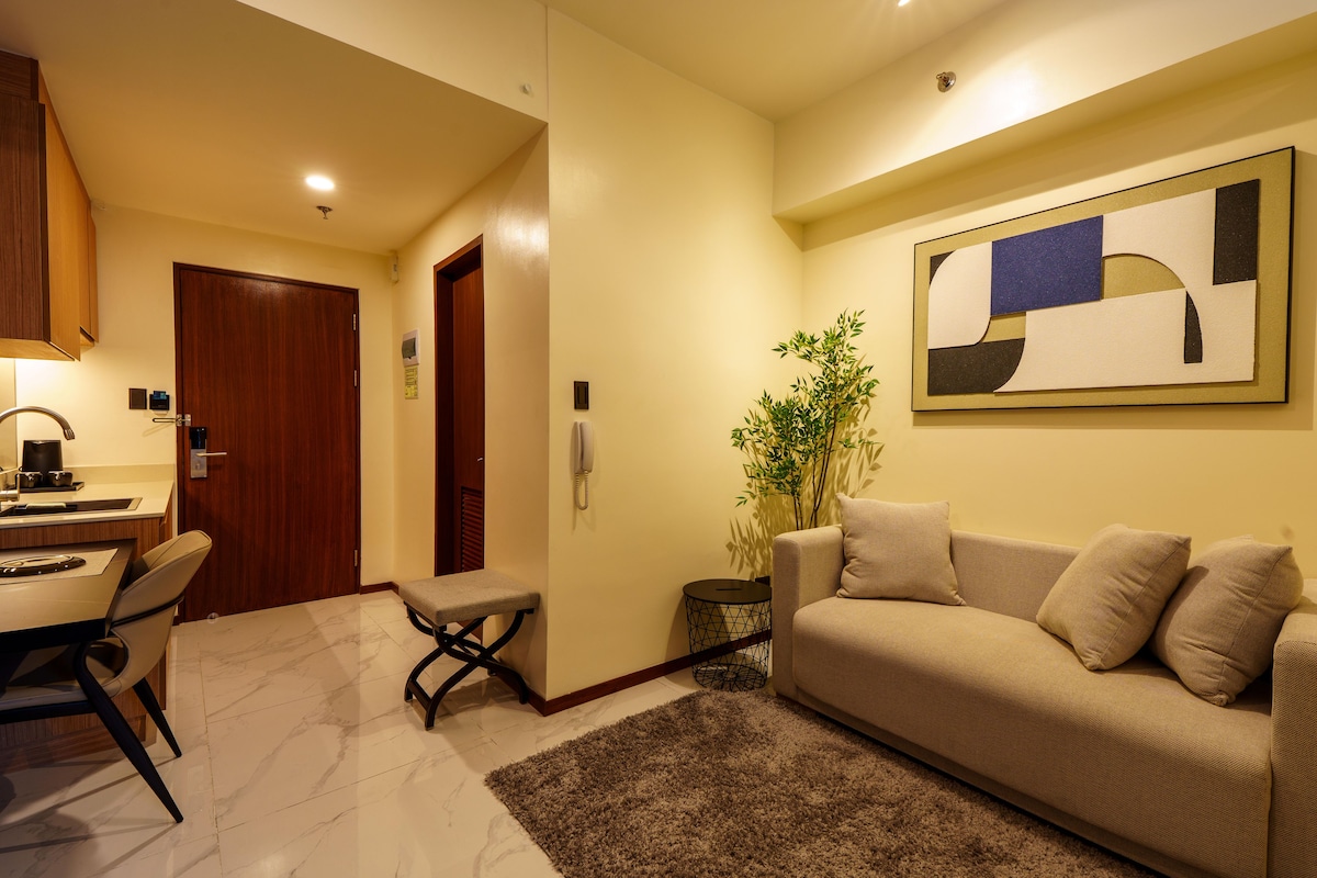 Una sala de estar moderna con un sofá, una mesa de centro, una zona de comedor con mesa y sillas, y un área de cocina con estufa.