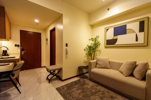 A modern living room with a sofa, a coffee table, a dining area with a table and chairs, and a kitchen area with a stove.