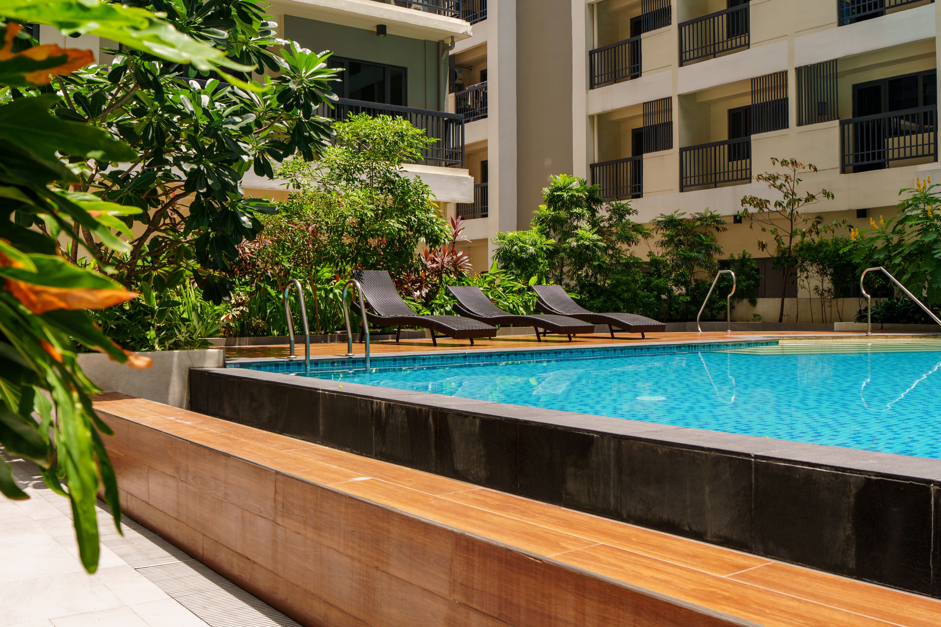 Una piscina con sillas de descanso y vistas a un edificio de varios pisos.