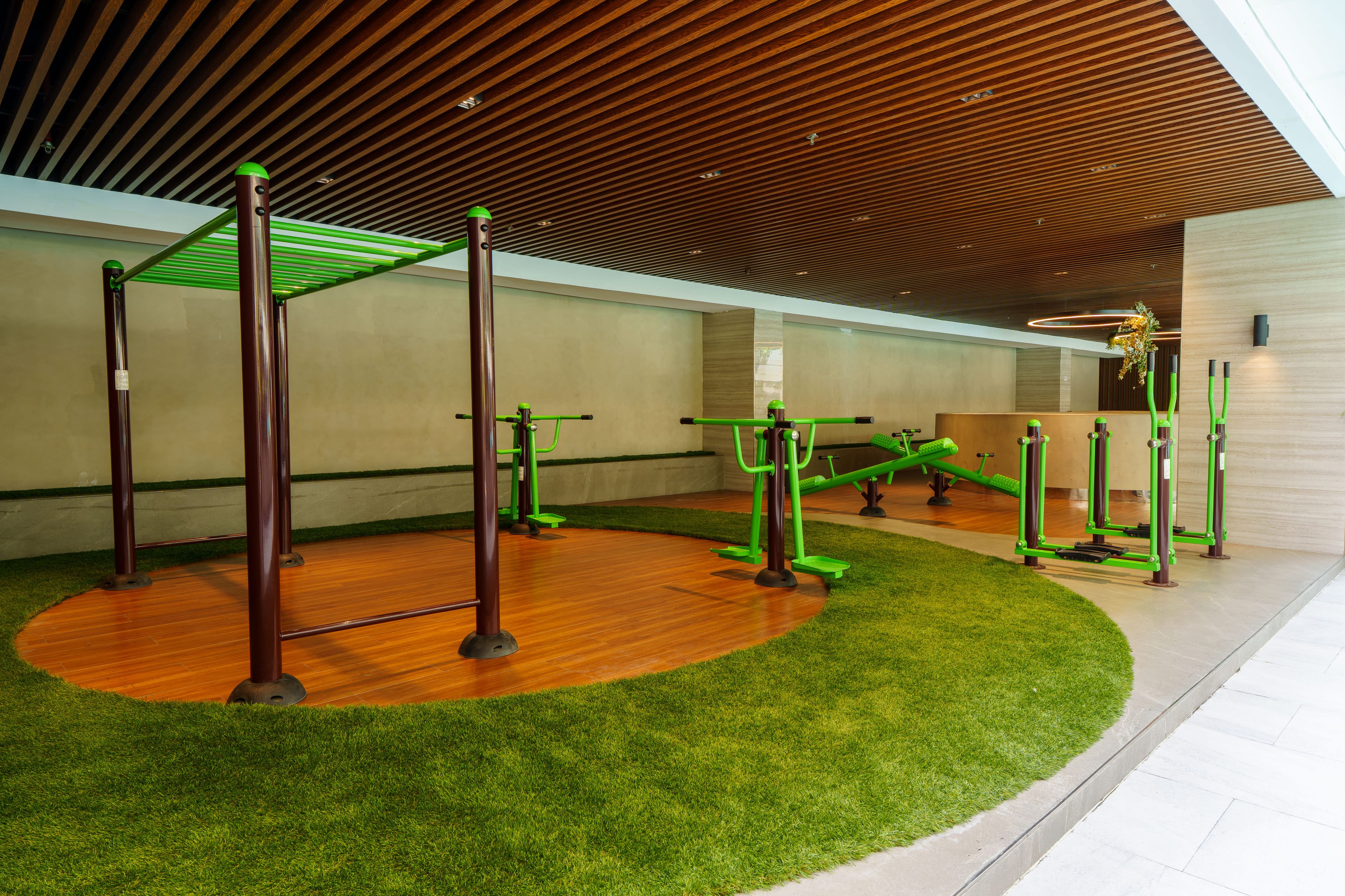 An indoor gym with exercise equipment, wooden flooring, and artificial grass.