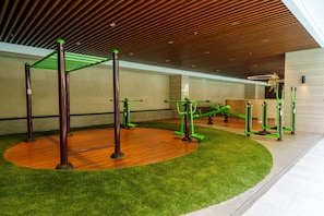 Un gimnasio interior con equipo de ejercicio, suelo de madera y césped artificial.