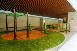 Un gimnasio interior con equipo de ejercicio, suelo de madera y césped artificial.