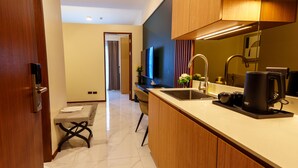 A modern kitchen with a marble countertop, wooden cabinets, a built-in oven, and a coffee machine. - SunnyPlace (Parañaque)