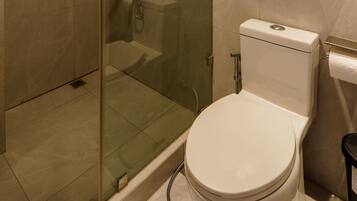 Une salle de bain moderne avec une douche en verre, des toilettes et une étagère sur laquelle est posée une plante en pot.
