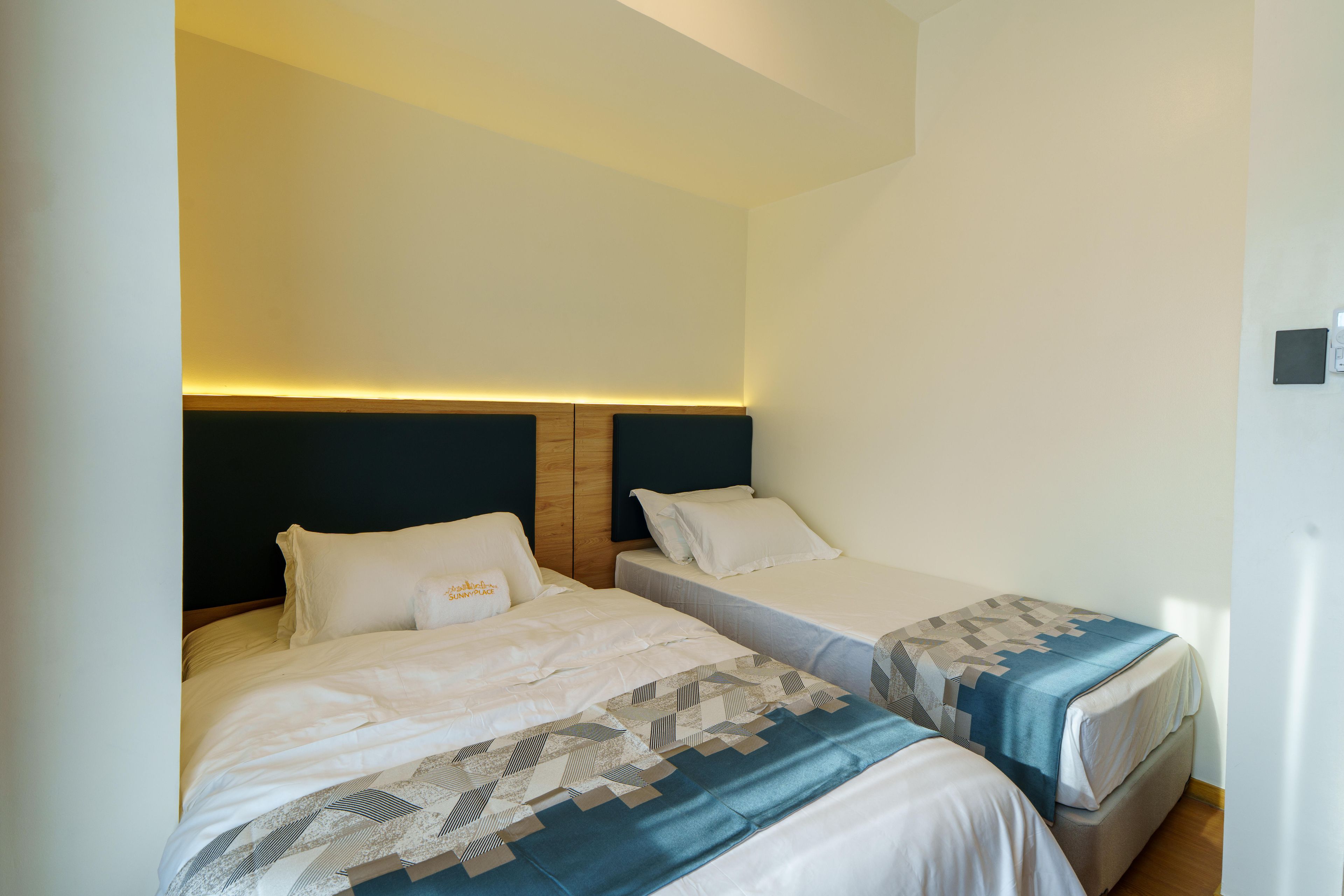 A hotel room with two single beds, a wooden headboard, and a bedside table with a lamp.