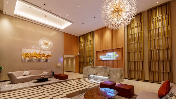 A modern lobby with a reception desk, sofas, a coffee table, and a large artwork. - SunnyPlace (Parañaque)