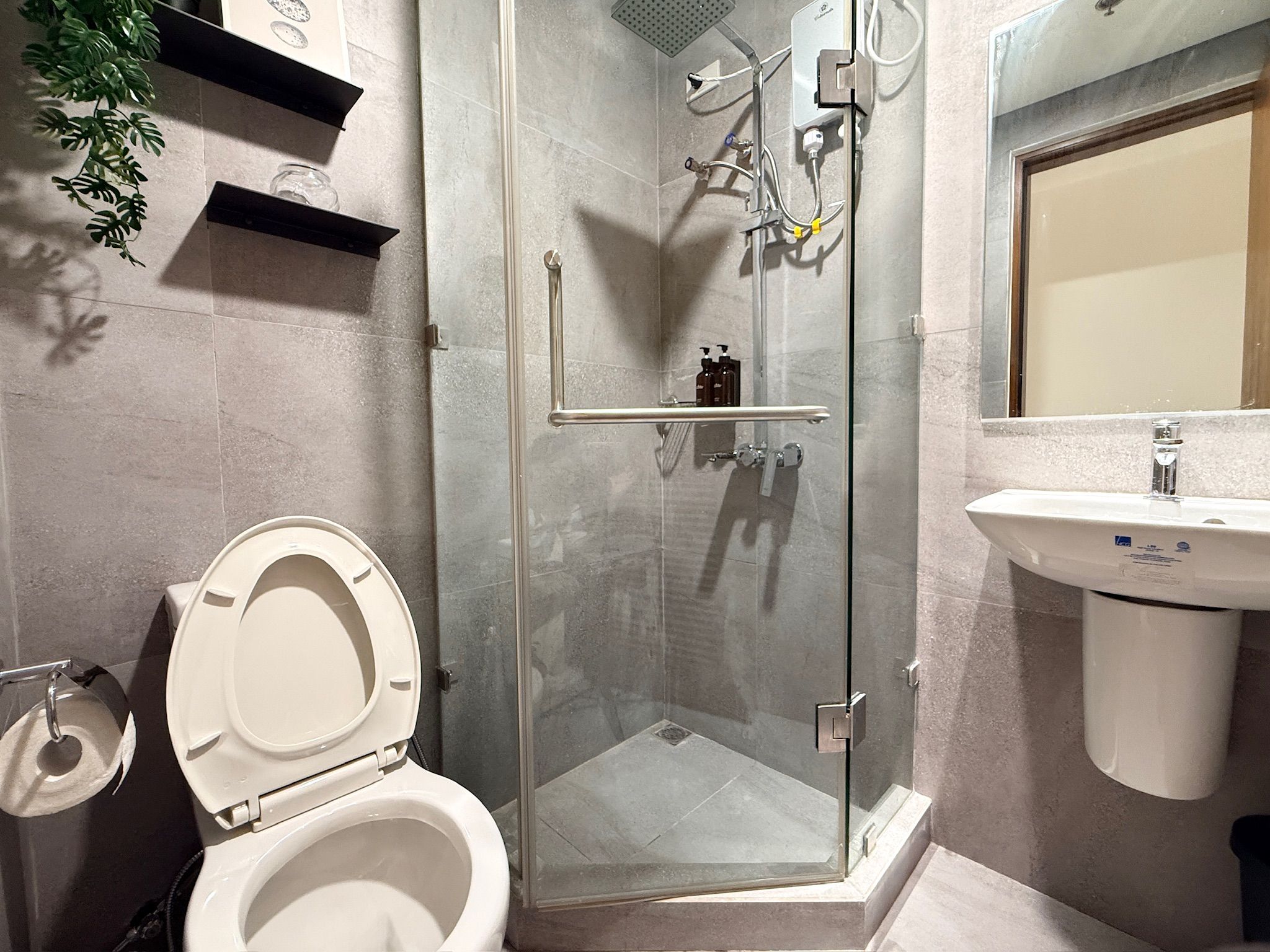 Un baño moderno con ducha envuelta en vidrio, inodoro y lavamanos.