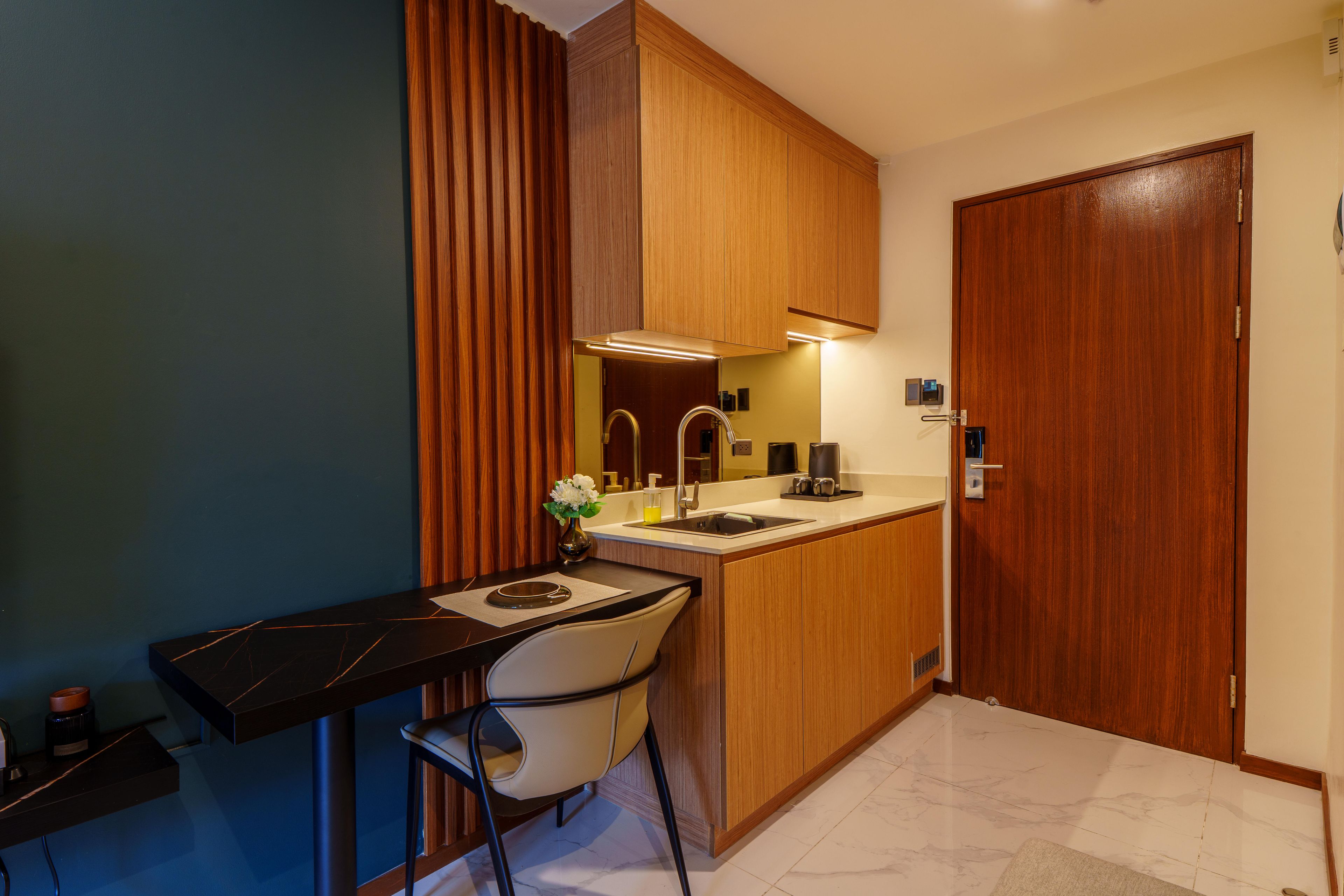 Una cocina compacta con comedor, armarios de madera, un lavamanos y una silla.