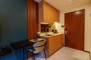 A compact kitchen with a dining area, wooden cabinets, a sink, and a chair.