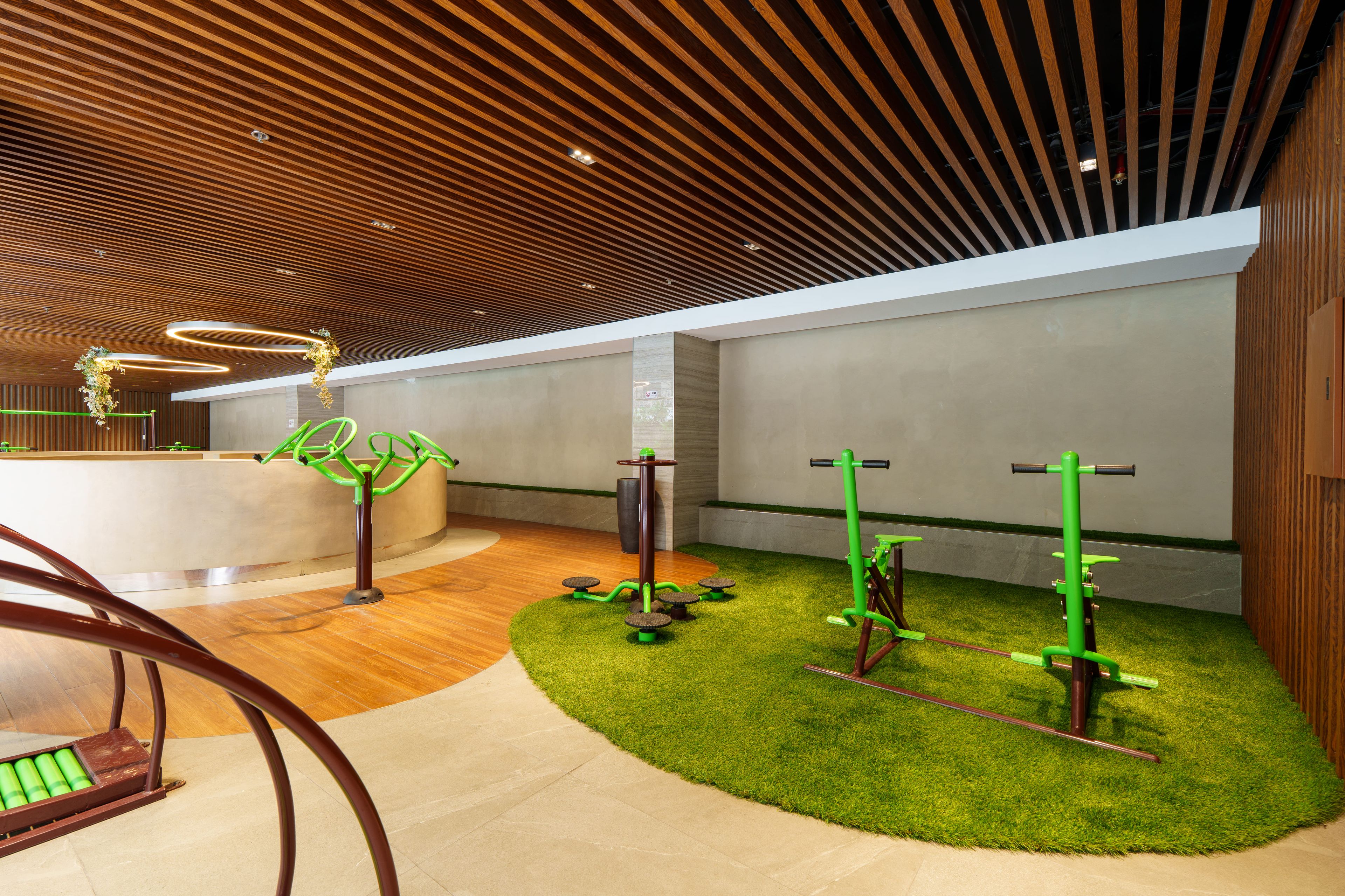 Un interior moderno con techo de madera, equipo de ejercicio y césped artificial.