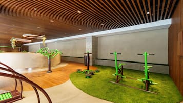 Un interior moderno con techo de madera, equipo de ejercicio y césped artificial.