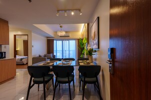 A modern dining area with a rectangular table, four chairs, and a chandelier.