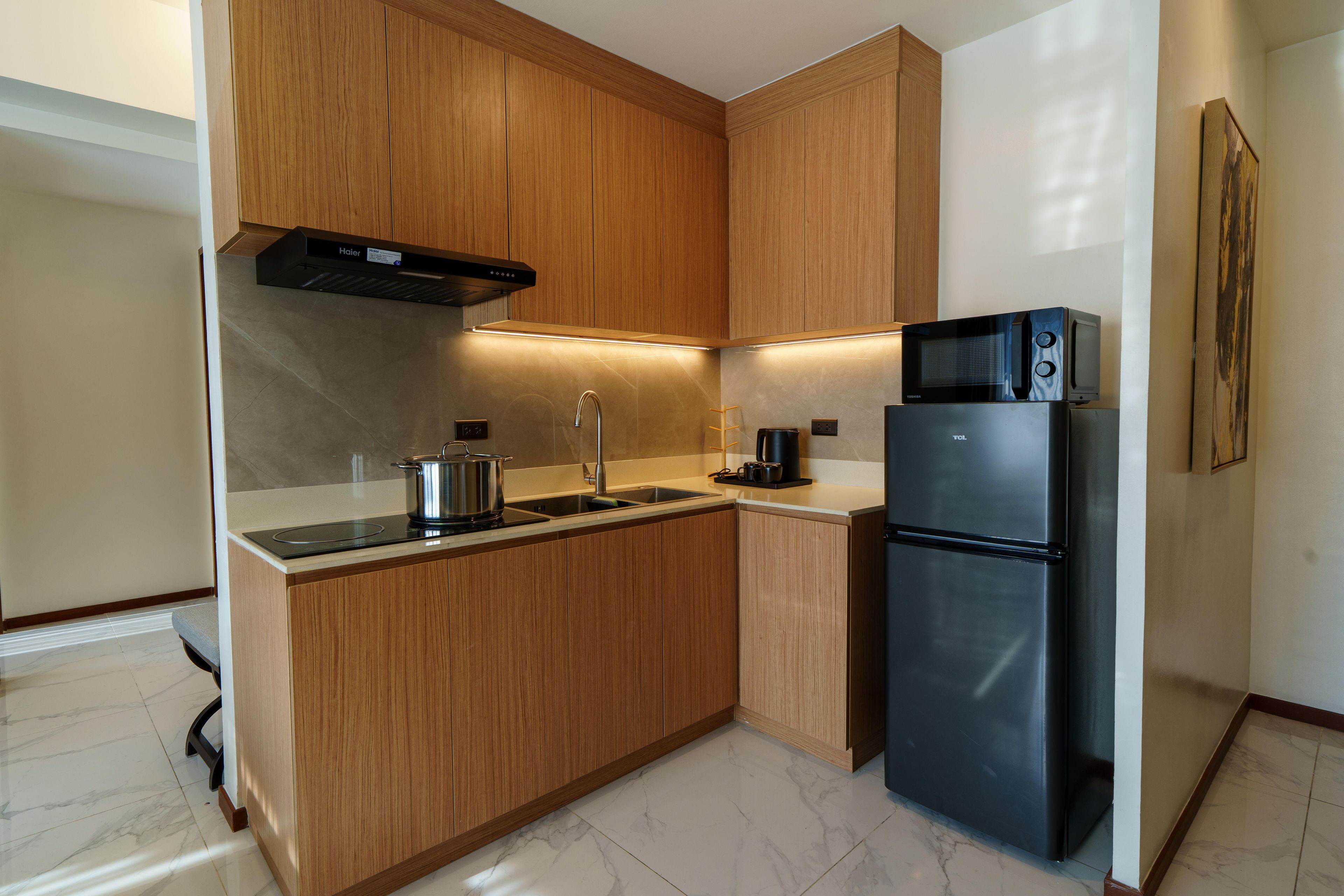 A modern kitchen with wooden cabinets, a stainless steel refrigerator, a microwave, and a stove.