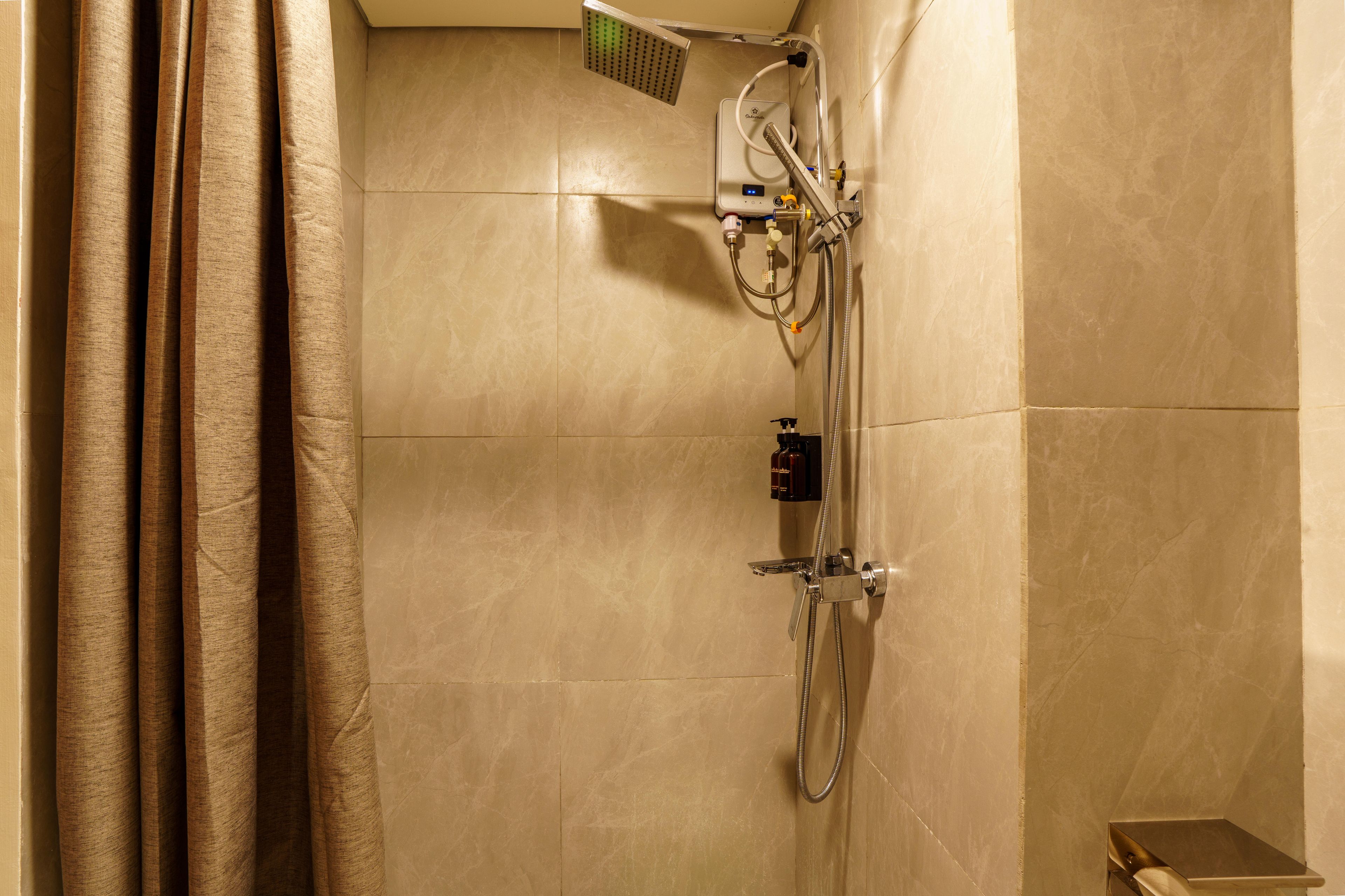 A shower with a handheld showerhead, a handheld shower attachment, and a wall-mounted control panel.