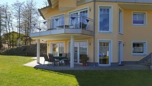 Um edifício residencial com vários andares, varanda, pátio com móveis de exterior e um gramado bem cuidado.