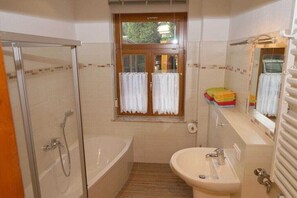 A bathroom with a shower, a bathtub, a sink, and a window with curtains. - A1 in the apartment building near Müritz (Waren (Müritz))