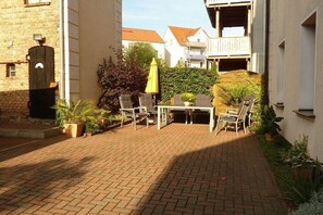 A courtyard with a brick floor, outdoor seating, and potted plants. - A1 in the apartment building near Müritz (Waren (Müritz))