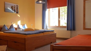 Ein Schlafzimmer mit einem Bett, einem Fenster mit Vorhängen, einem Heizkörper und einem Bild an der Wand.