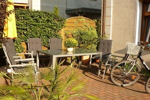 An outdoor patio with a table and chairs, surrounded by plants and a bicycle. - A1 in the apartment building near Müritz (Waren (Müritz))