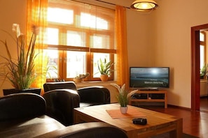 A living room with a television, leather chairs, a wooden coffee table, and potted plants. - A1 in the apartment building near Müritz (Waren (Müritz))