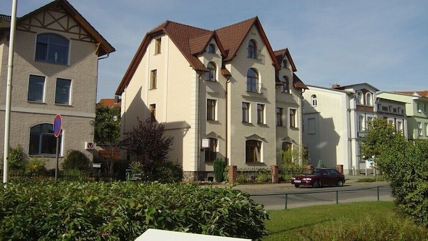 Ein mehrgeschossiges Wohngebäude im klassischen Stil, mit einer symmetrischen Fassade, zahlreichen Fenstern und einem zentralen Eingang.