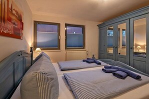 A bedroom with two beds, a wardrobe, and a window with blinds. - Holiday home with 2 bedrooms (Klein Labenz)