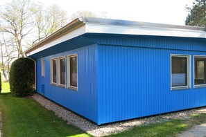 A blue building with a flat roof, rectangular windows, and a gravel pathway leading to it. - Holiday home with 2 bedrooms (Klein Labenz)