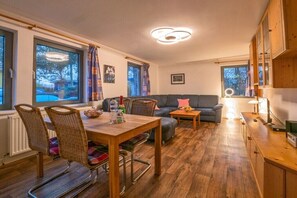 Ein gemütlicher Wohnbereich mit Esstisch, Stühlen, einer Couch und einem Fernseher.