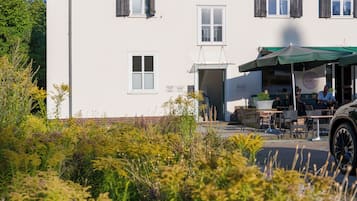 A two-story building with a flat roof, multiple windows, and a small outdoor seating area with tables and chairs.