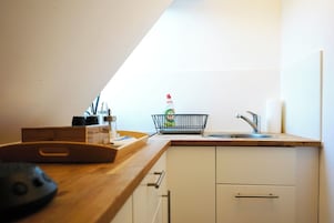 A kitchen with a wooden countertop, a sink, and a dish rack.
